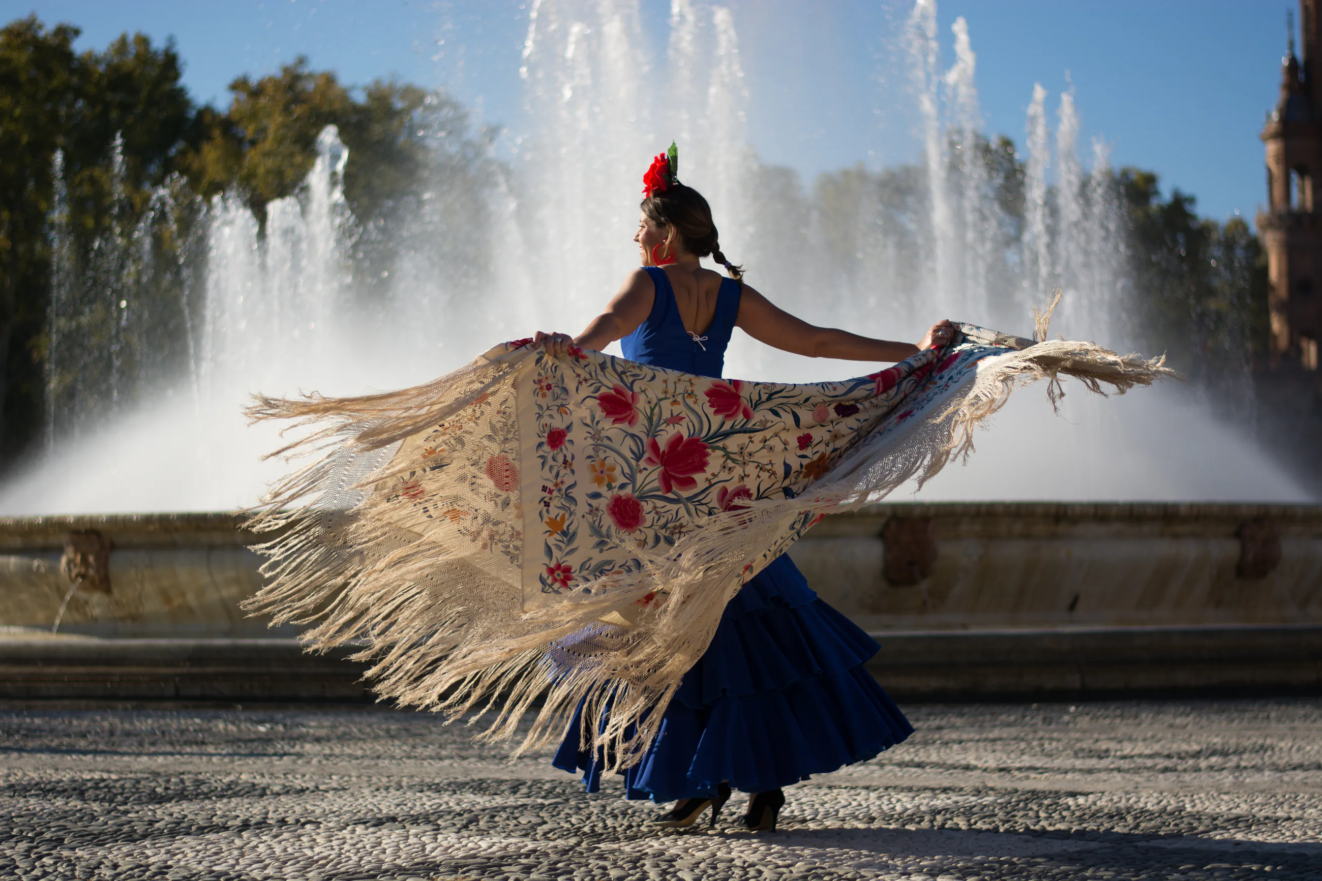 Woman in traditional Spanish dress celebrating beside a fountain