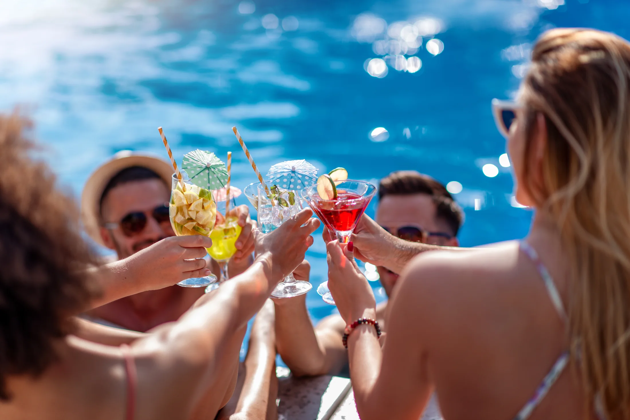 Friends celebrating together beside a sunlit pool